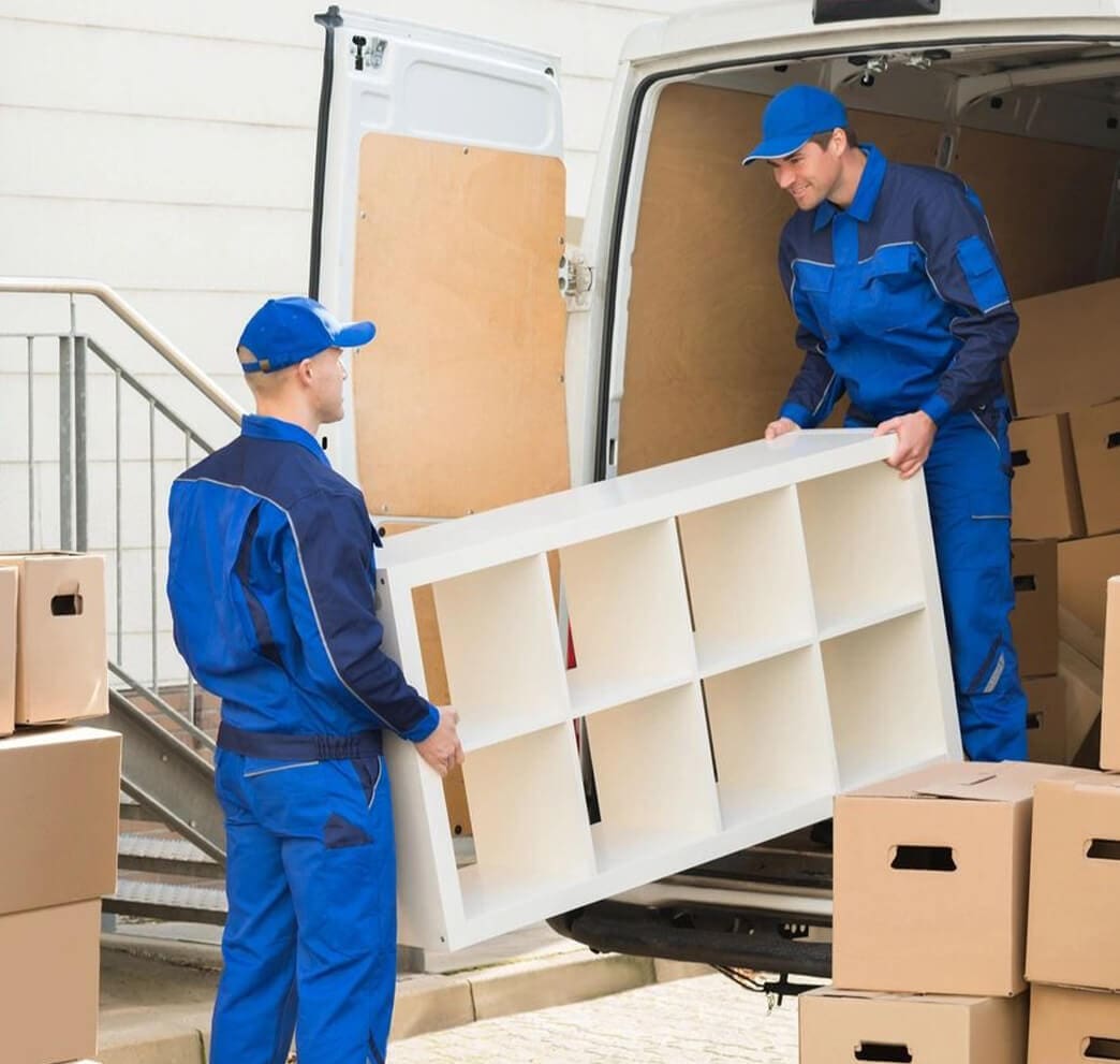 Two men in blue work clothes unloading a white truck.