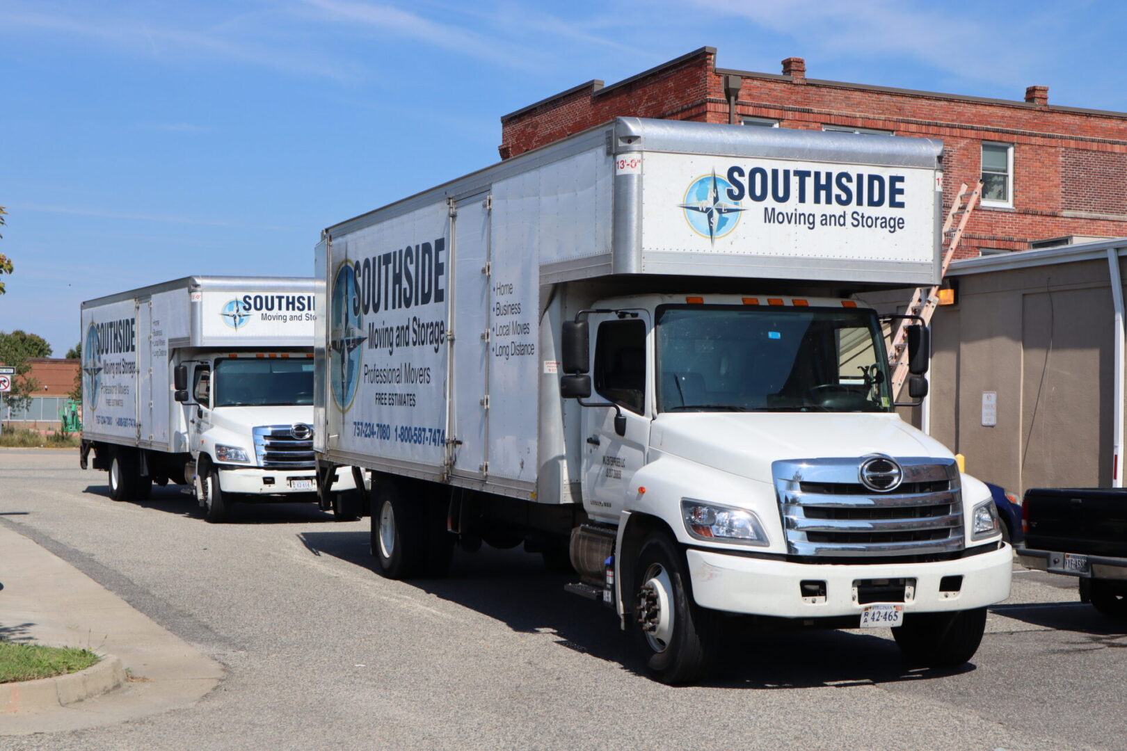 Two white trucks parked on the side of a road.