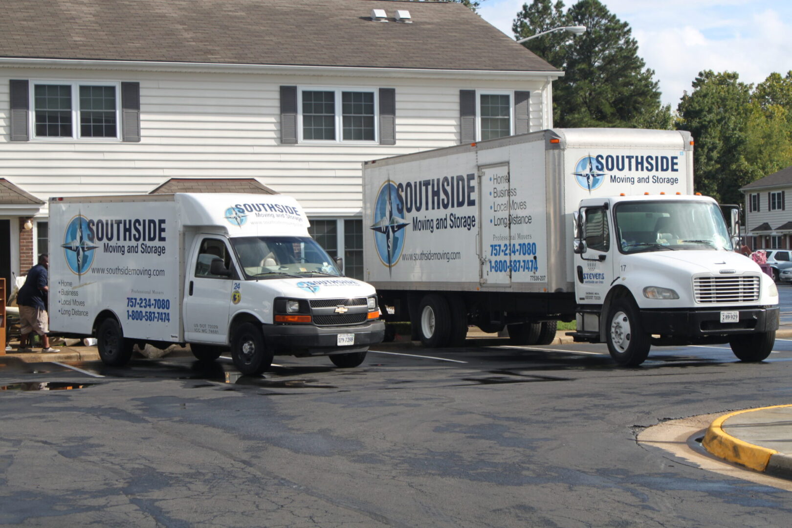 Two white trucks parked in front of a house.