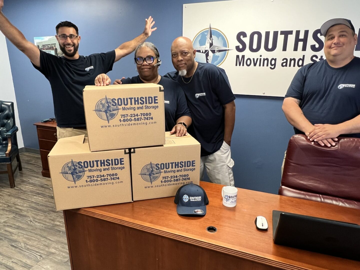 A group of people standing around boxes in an office.