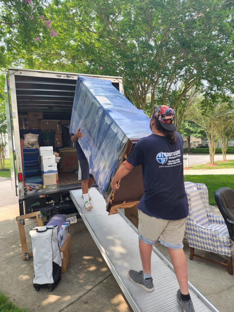 A man standing next to a truck with furniture.