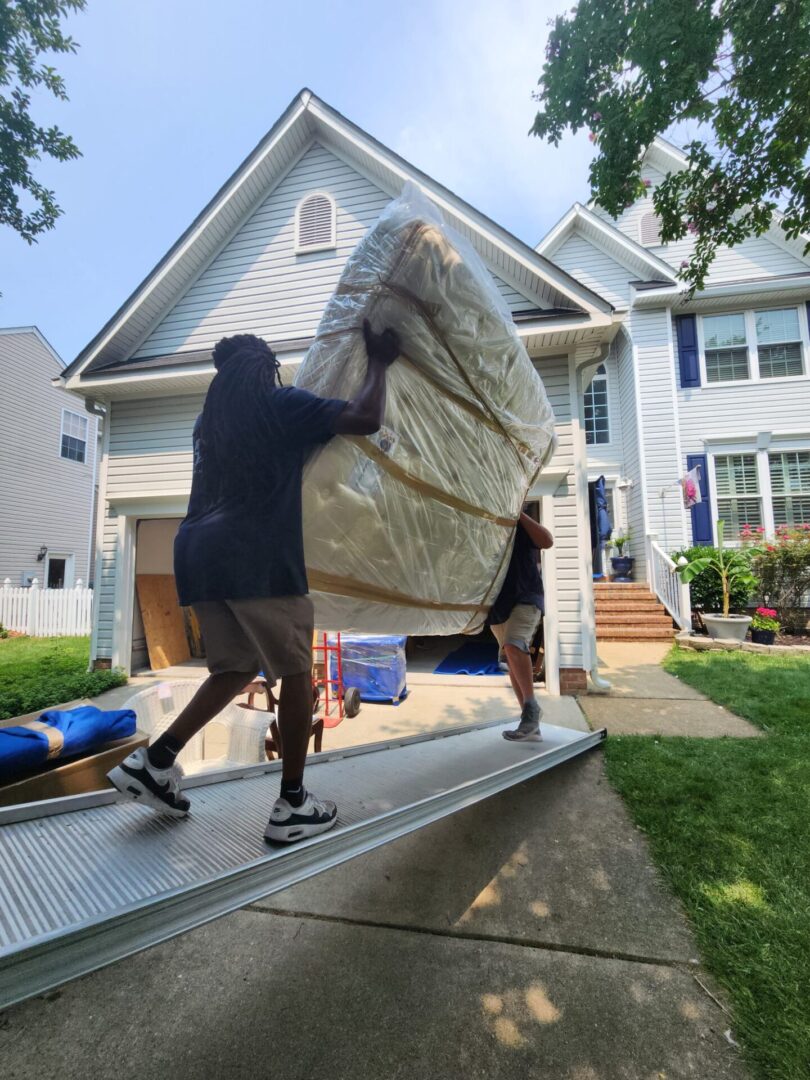 Two men moving a couch on the back of a truck.