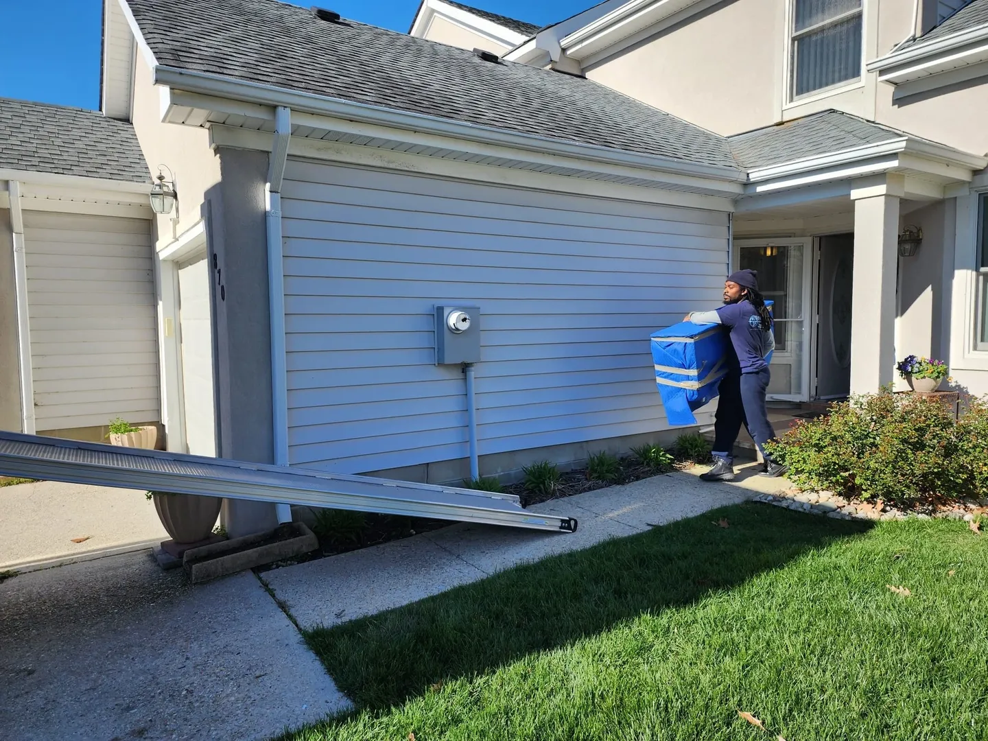 A man carrying a blue water bottle into a house.