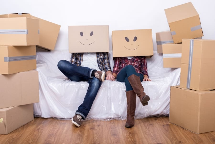 Two people sitting on a couch with boxes on their heads