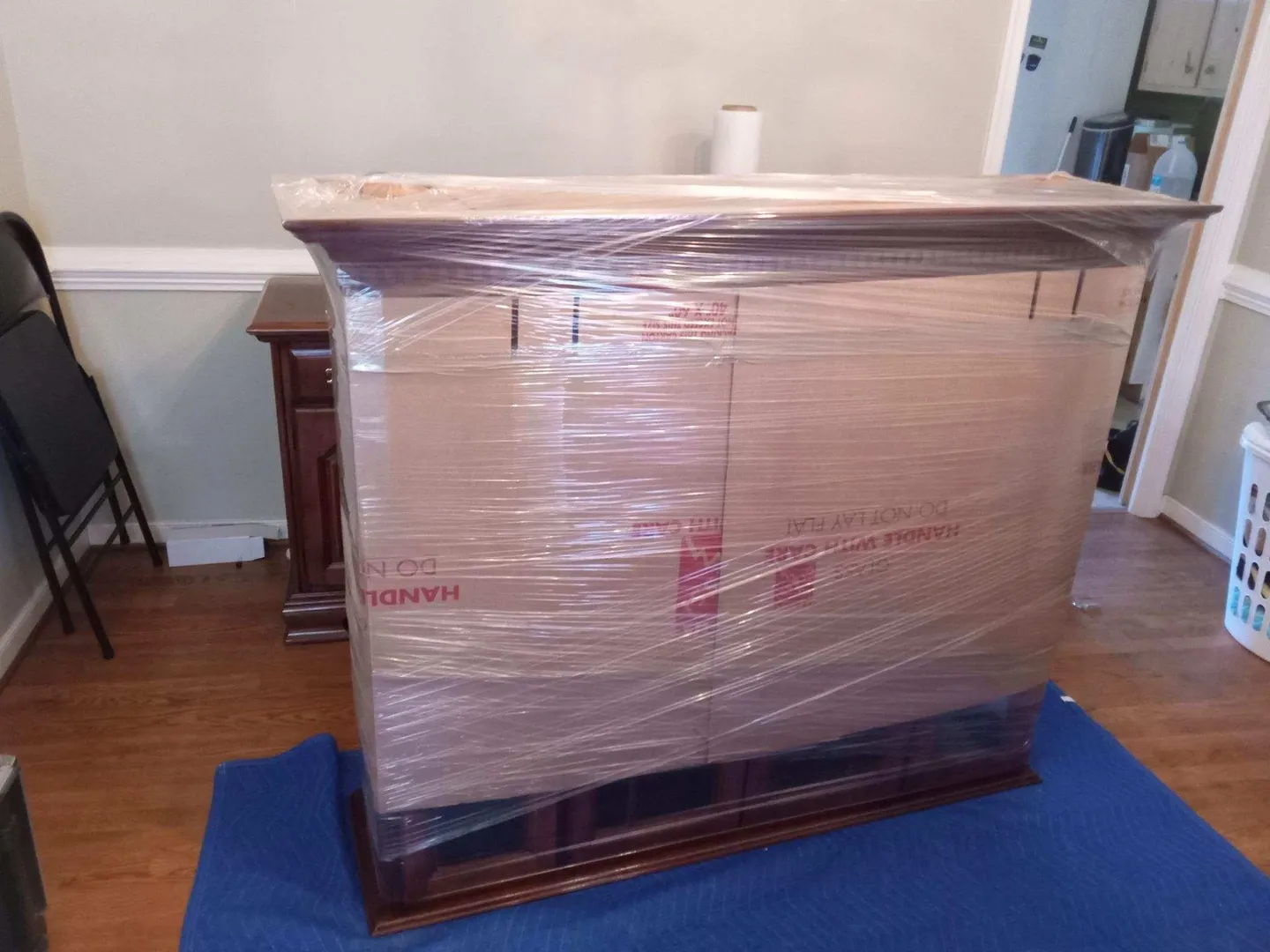 A wooden table covered in plastic wrapped boxes.