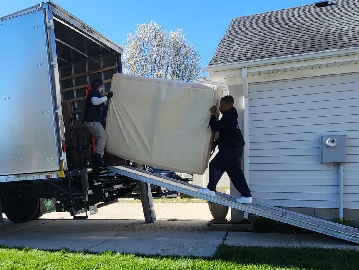 A man is loading furniture onto the back of a truck.