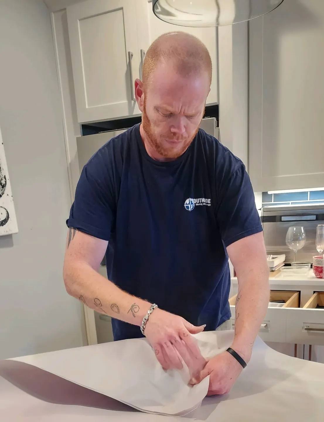 A man in blue shirt cutting paper with scissors.